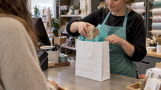 Medewerker stopt cadeau in een cadeauzakje
